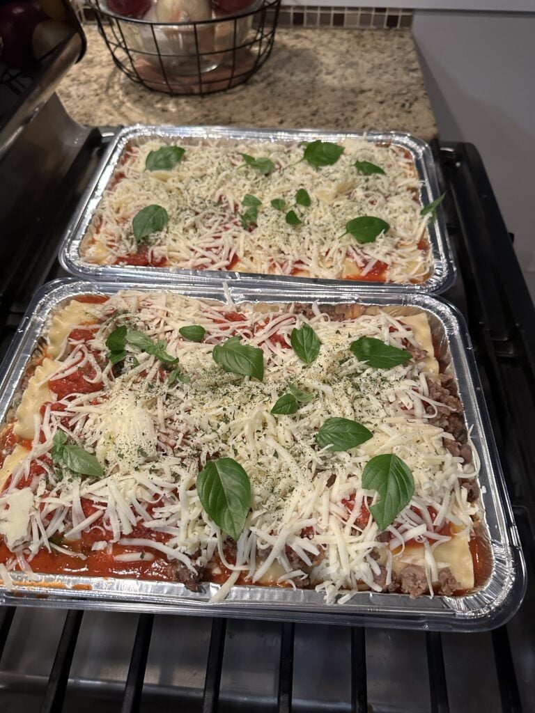 The two lasagnas topped with shredded cheese and basil before being put in the oven