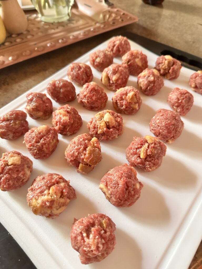 Raw ground beef formed into balls on a white cutting board
