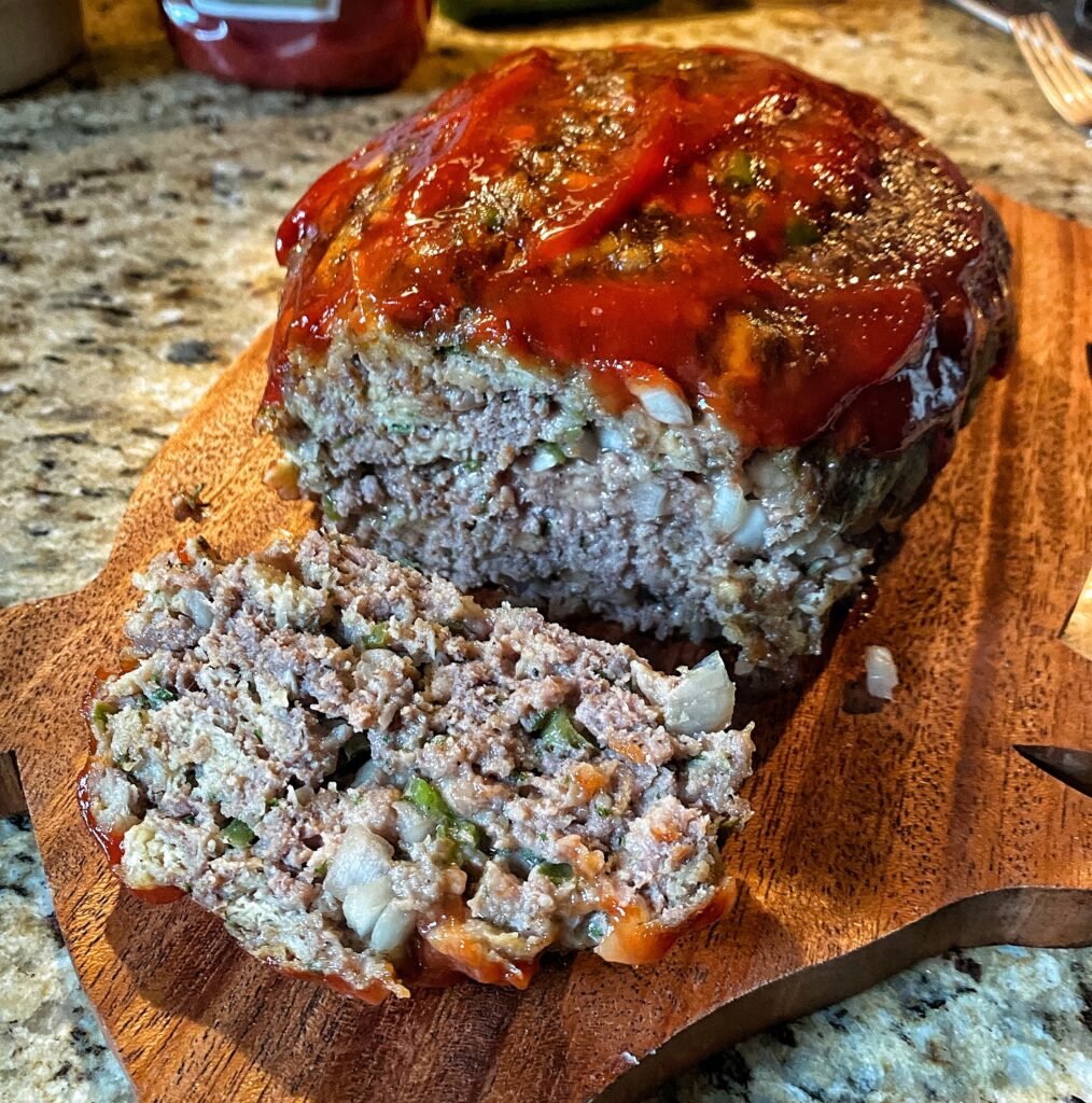 Meatloaf with a slice taken from it with red glaze on top