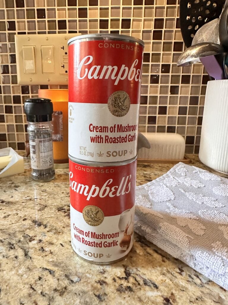 Two cans of Campbell's "Cream of Mushroom with Roasted Garlic" soup stacked on top of each other