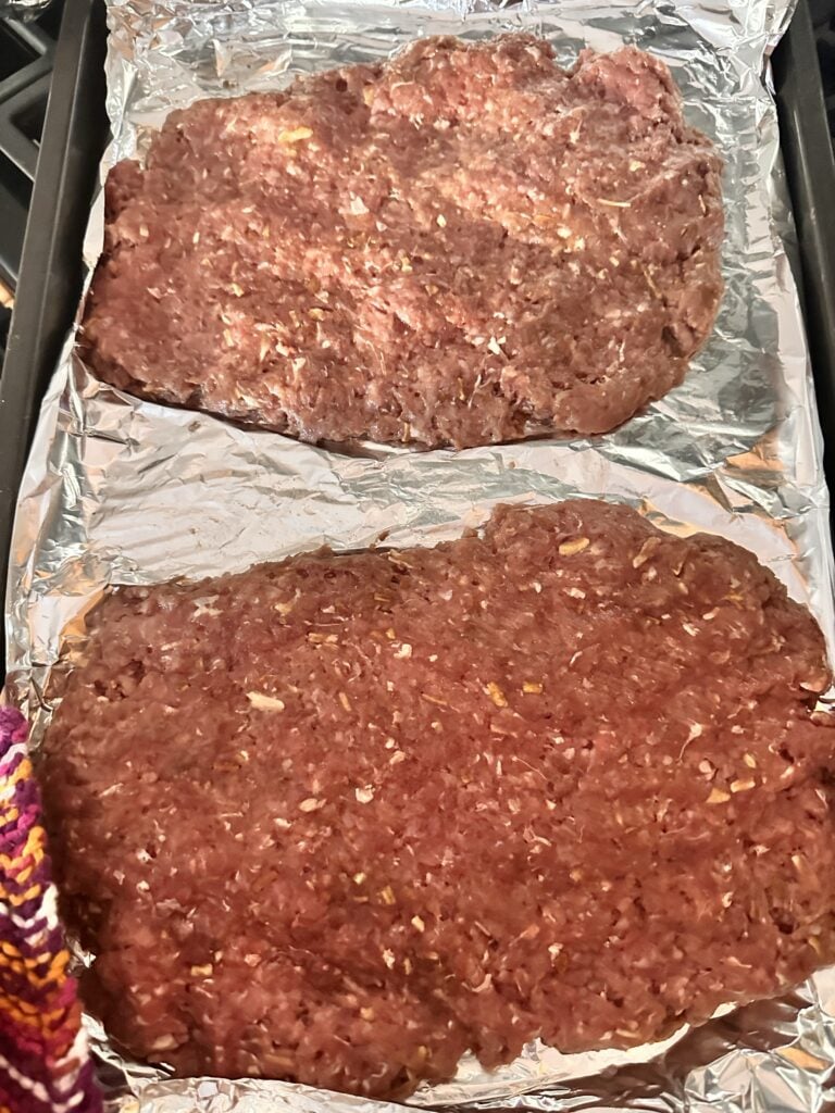Two patties of raw ground beef on foil