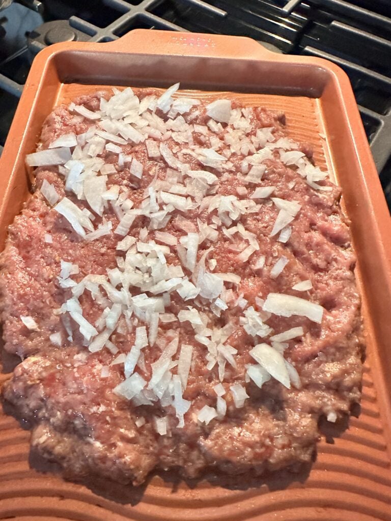 Flattened, raw ground beef topped with diced onions