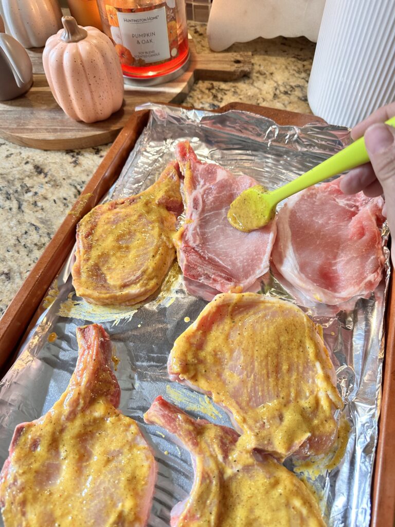 A sauce mixture being spread on raw pork chops
