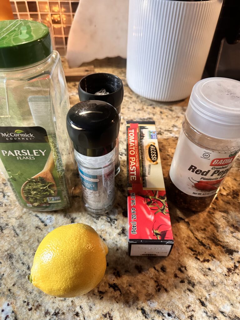 Various spices, seasonings, and a lemon on a kitchen counter.