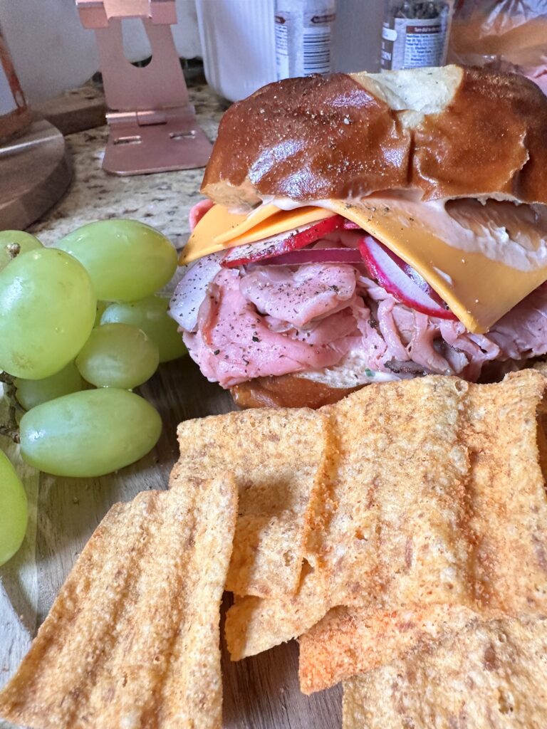A close up of the finished roast beef sandwich with grapes and Sun Chips.