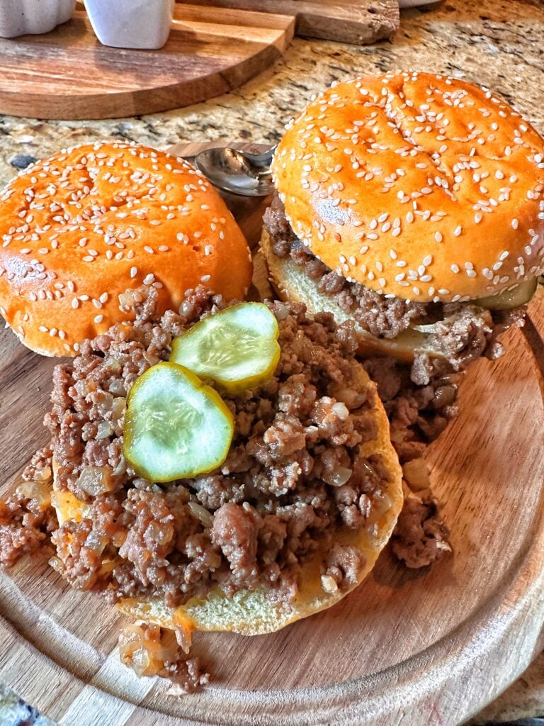 Two Maid Rite sandwiches, one with the top bun removed to show the ground beef inside.