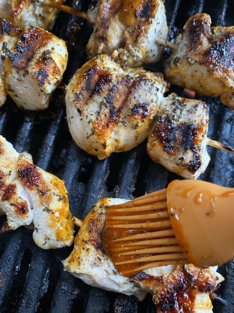 Marinade being applied to a chicken skewer with a brush