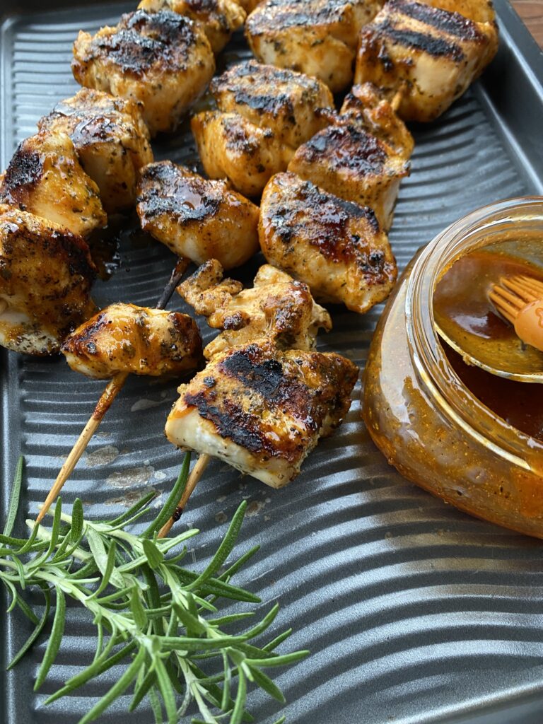 Grilled chicken skewers in between rosemary and marinade