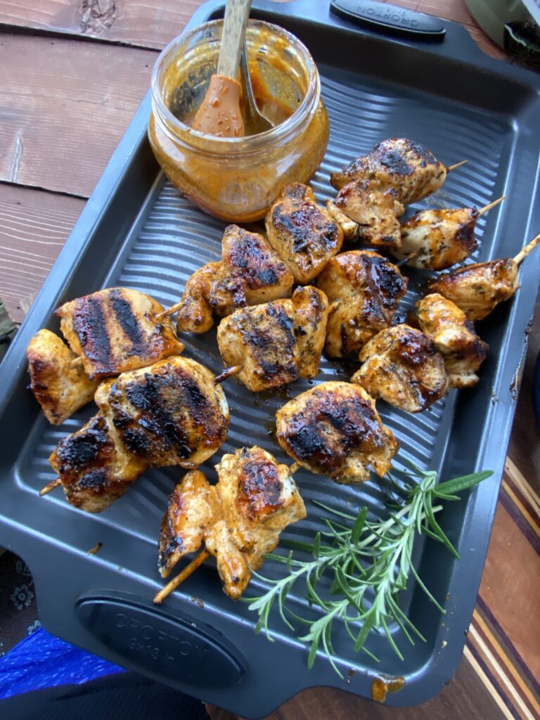 Chicken skewers, marinade, and rosemary on a pan