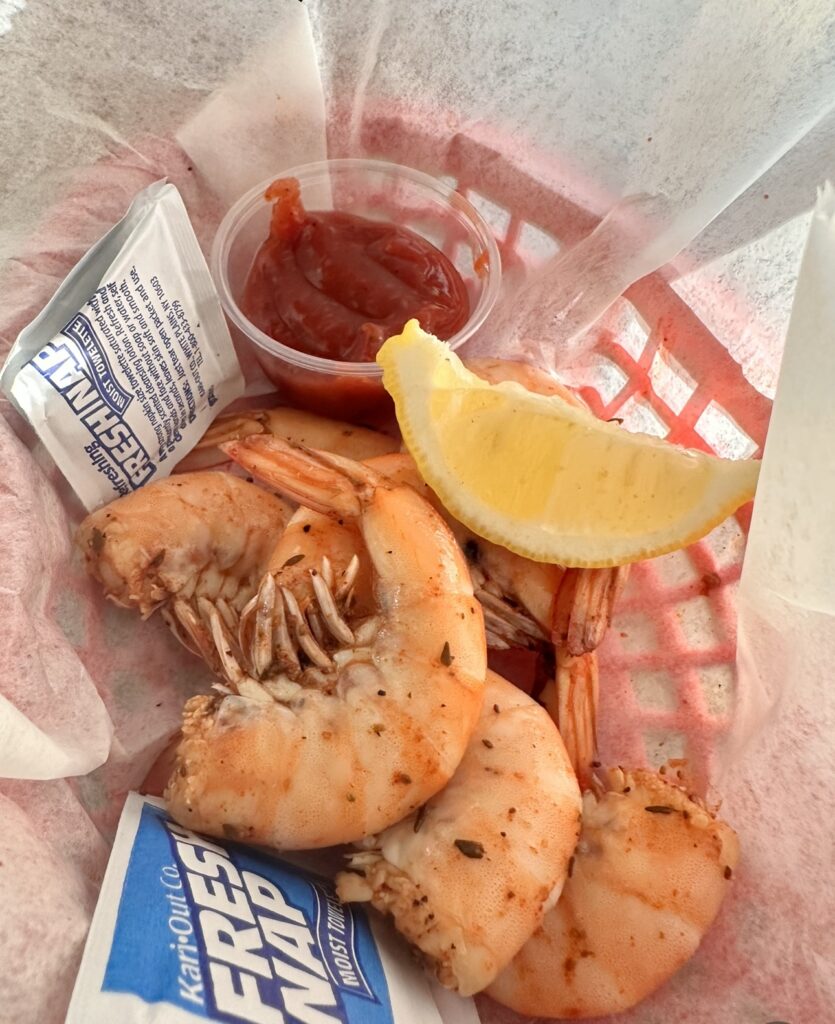 Shrimp with a lemon wedge and cocktail sauce.