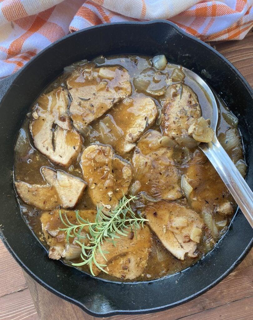 Pork roast and dumplings with gravy in a cast iron pan.