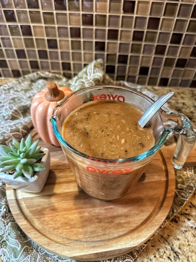 Turkey Gravy with a metal spoon in a glass measuring container
