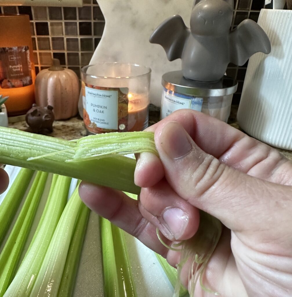 The outer layer of the celery is being pulled away