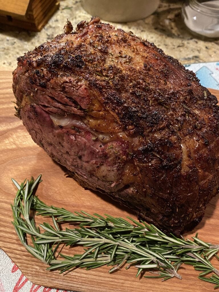 Perfectly cooked rib roast next to rosemary