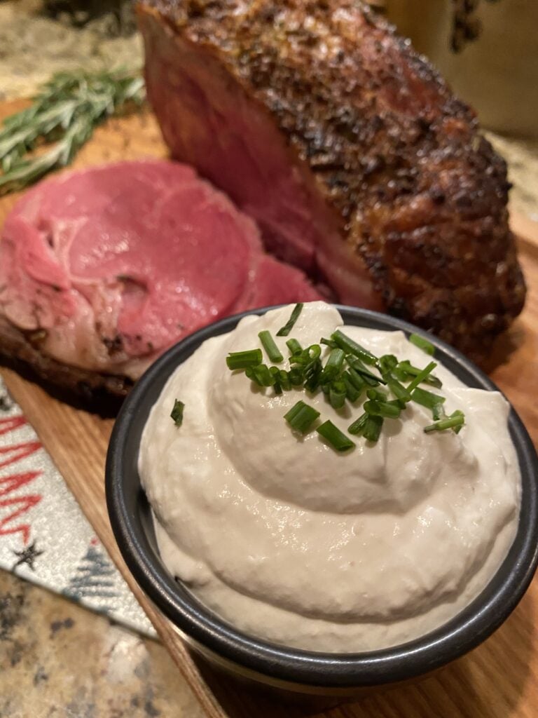Horseradish cream sauce next to a slice of rare rib roast