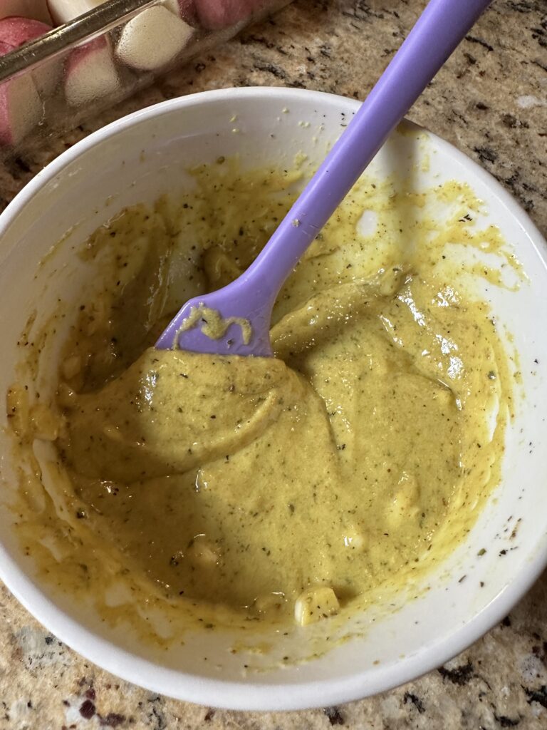 A bowl with the sauce mixture for the potatoes and a ladle for mixing
