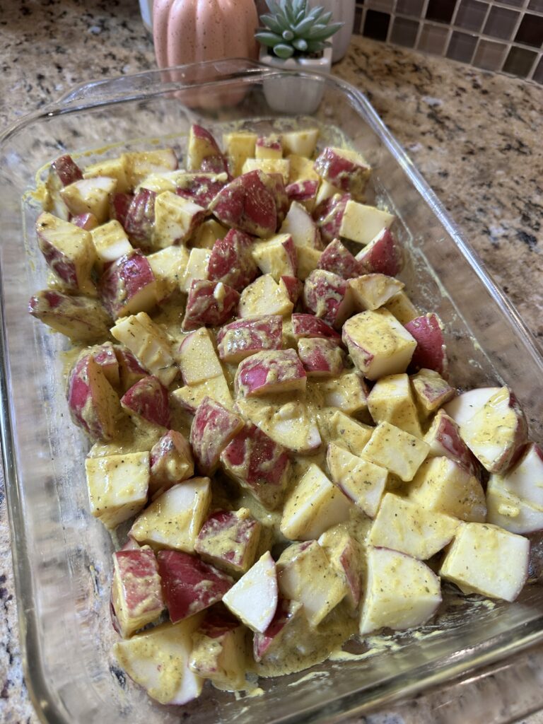 Raw potatoes in a baking dish with sauce spread over them
