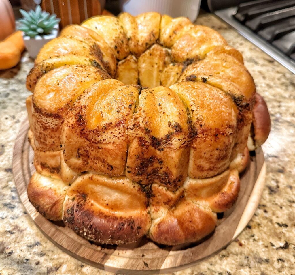 Buttery herb pull apart dinner roles on a wooden plate