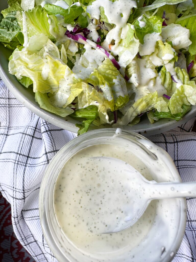 Salad dressed with Aloha dressing next to a container of Aloha dressing with a spoon in it