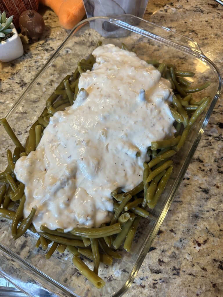 Green beans in a glass baking dish covered in white sauce
