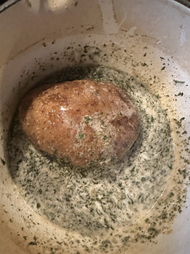A sliced potato placed slice side down in the butter mixture