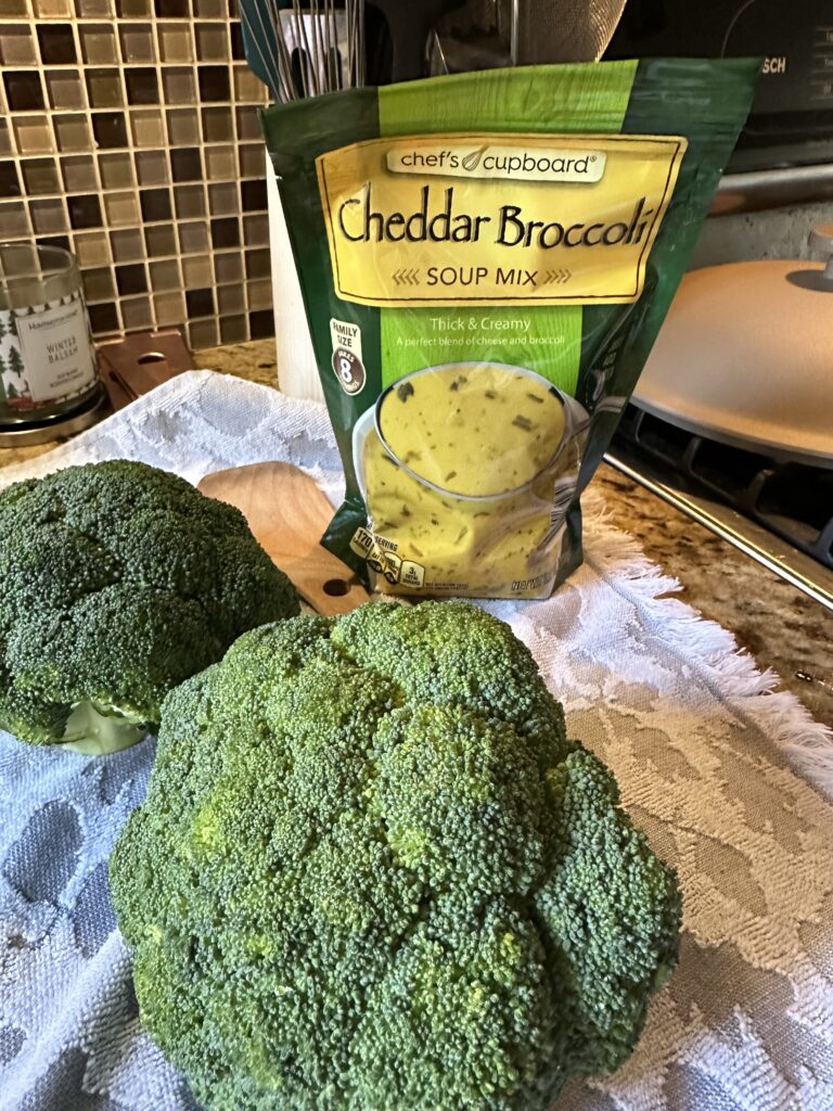 Raw broccoli in front of a bag of cheddar broccoli soup mix