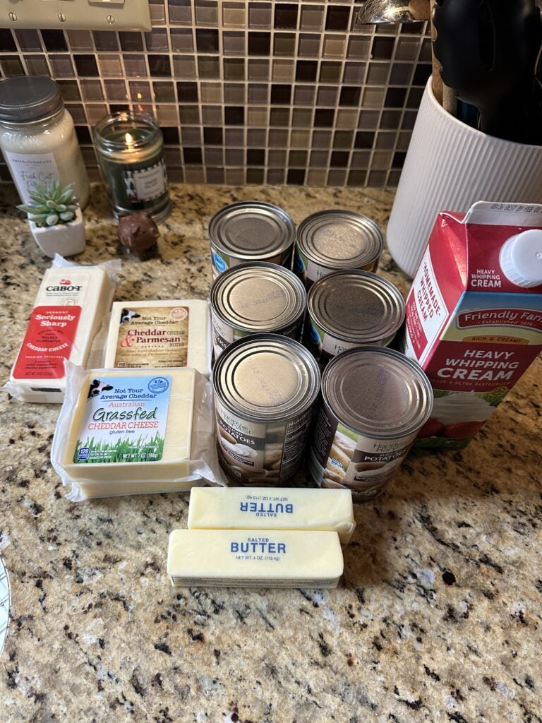 Butter, cheese, cans of potatoes, and heavy whipping cream on a counter