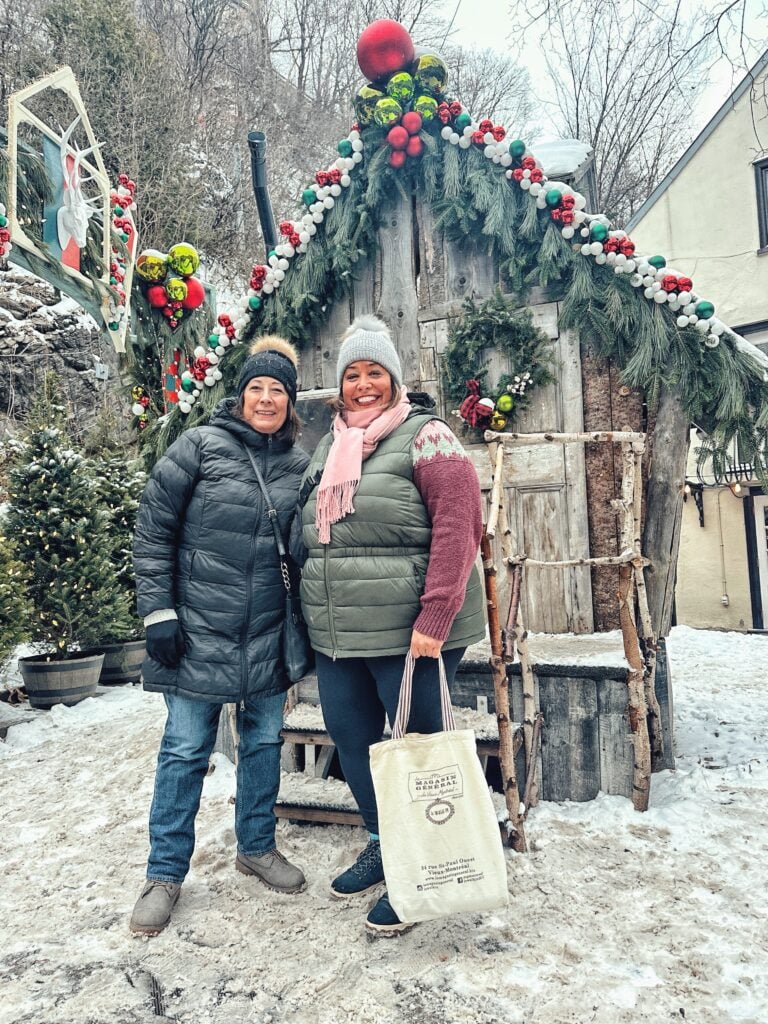 Mom and me in front of a quaint mini Christmas cabin