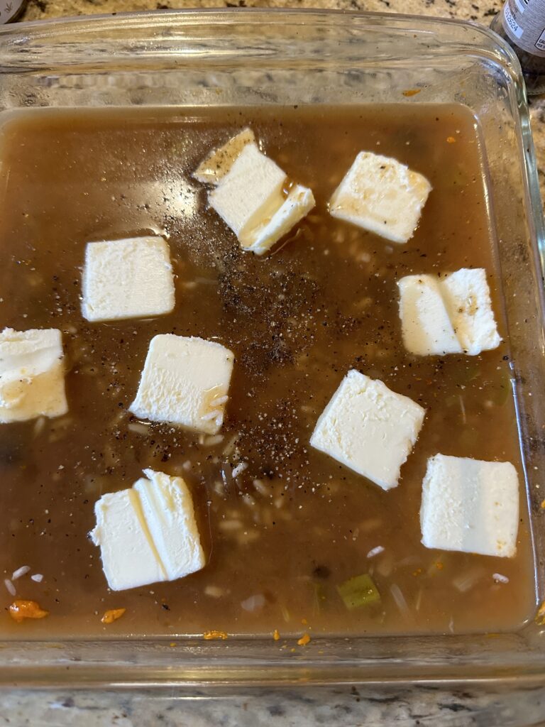 Pats of butter in a sauce in a baking dish