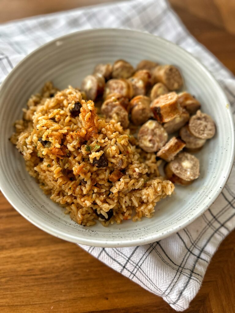 Baked rice in a bowl next to sliced sausage