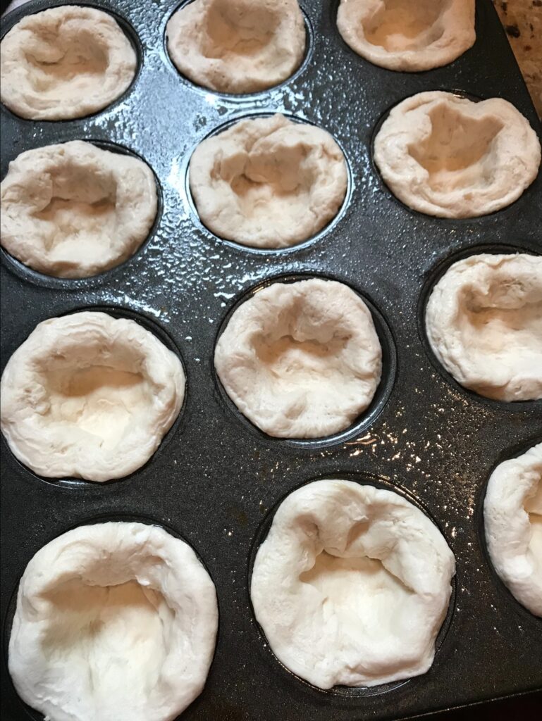 Raw biscuit dough in a muffin tin