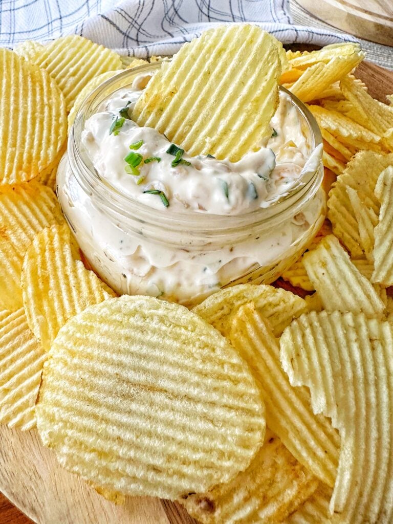 A chip dipped in onion dip surrounded by other chips