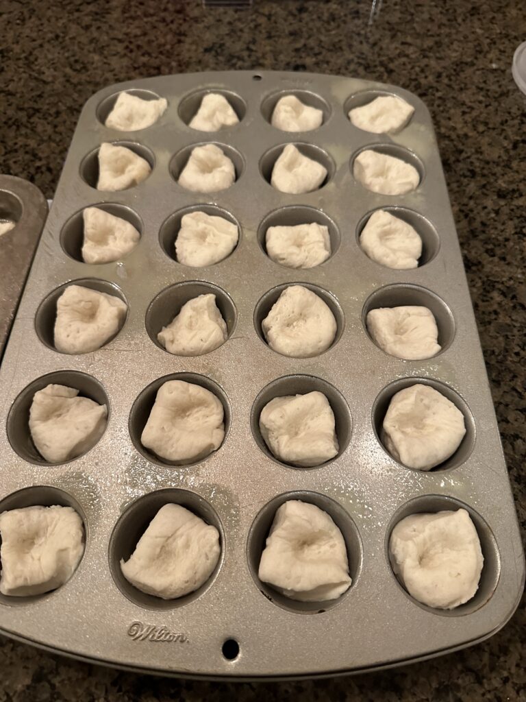 Raw biscuit dough in a muffin tin