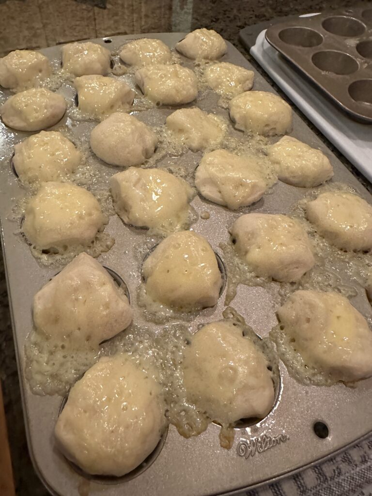 Cheese melting over biscuit dough in a muffin tin