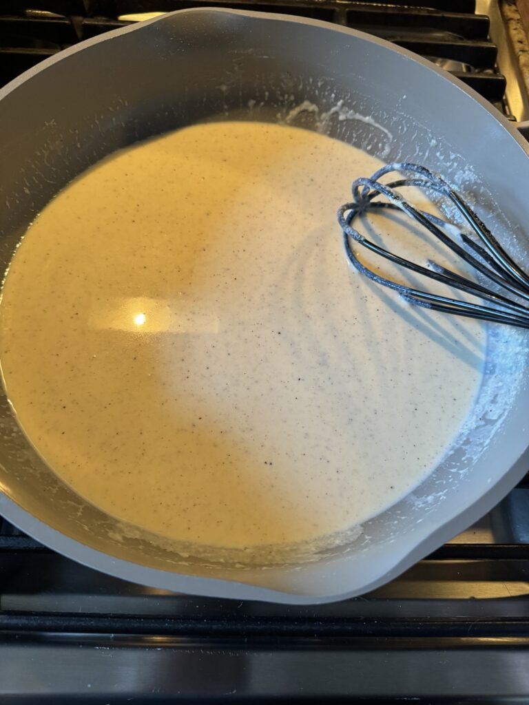 Cheese sauce in a pan with a whisk in it
