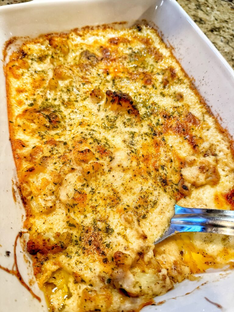 Baked Cheesy Cauliflower with a metal ladle in it