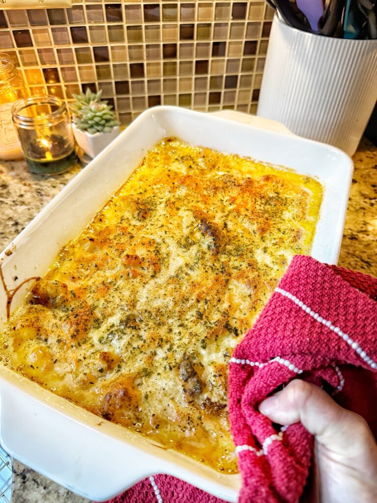 A finished baking dish full of cheesy cauliflower being held by a hand with wash cloth