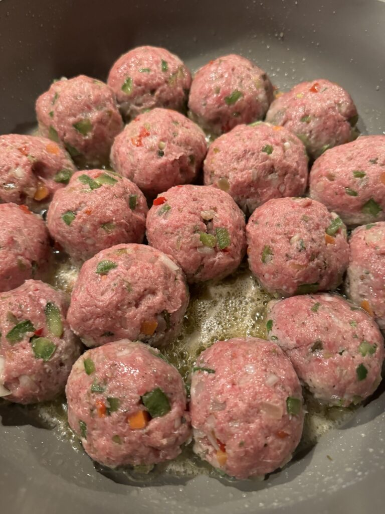 Raw Italian Beef meatballs beginning to cook