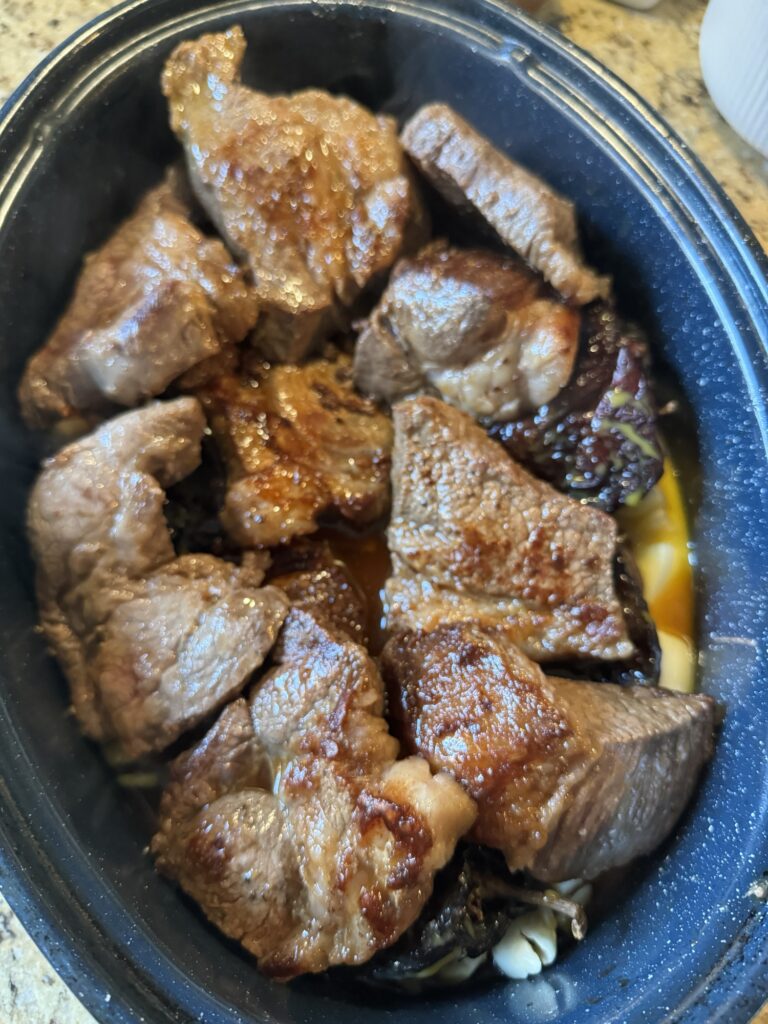 The meat chunks cooking in a roaster