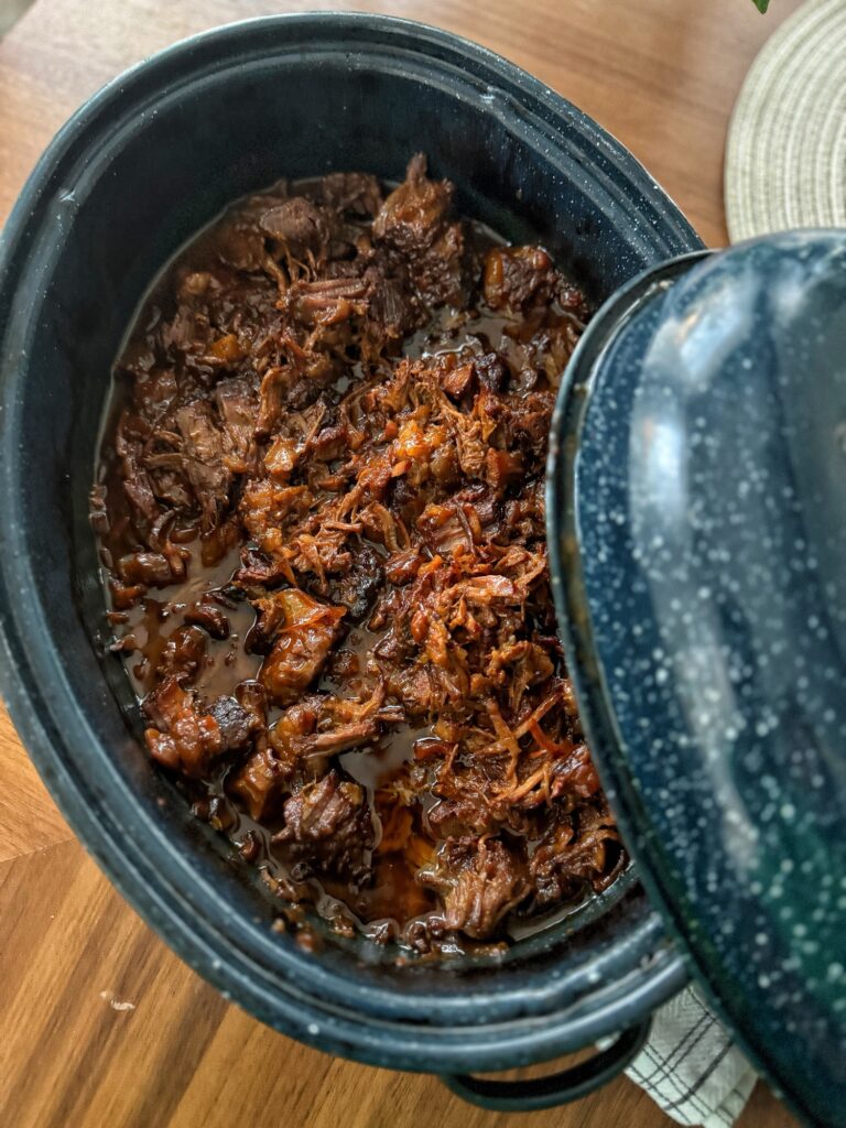 The finished shredded tangy beef in a roaster