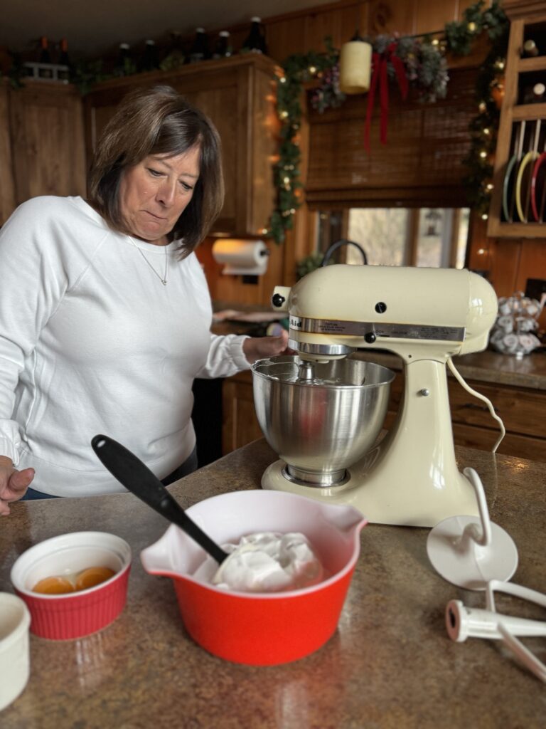 My mom using a mixer to prepare the cheesecake ingredients on the countertop