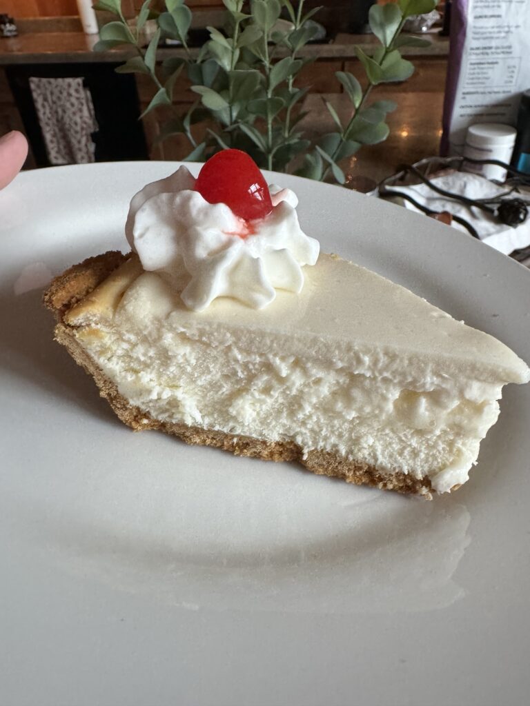 A slice of cheesecake with whipped topping and a cherry on top