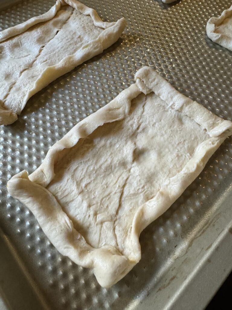 A close up of a raw crescent dough roll with the edges rolled up