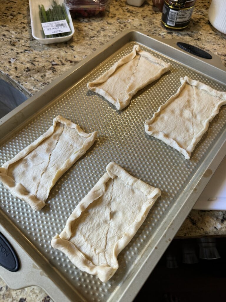 Raw crescent roll dough folded out on the baking sheet