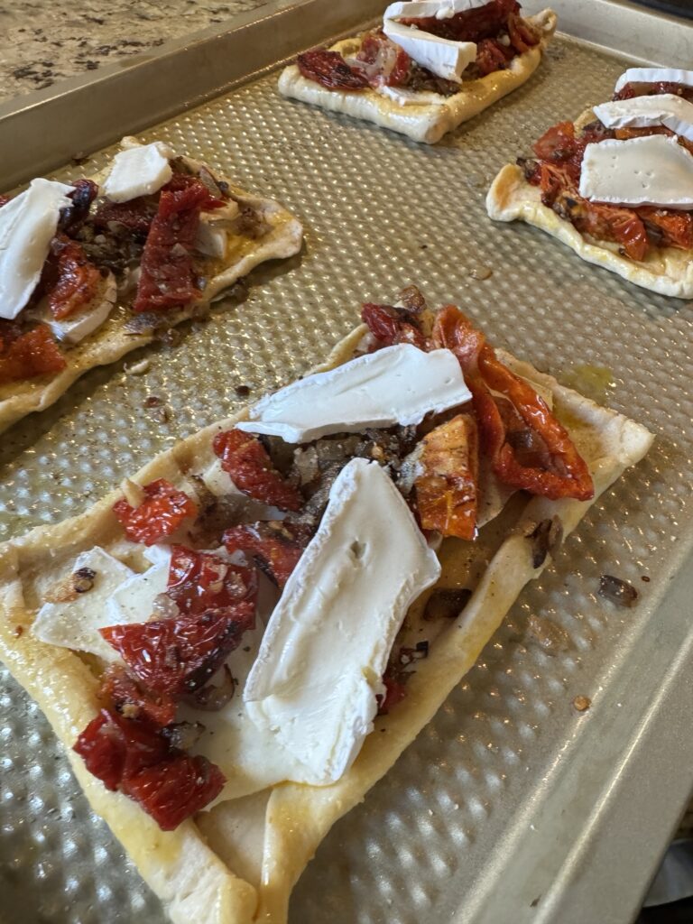 The raw crescent rolls topped with brie, shallots, and dried tomatoes