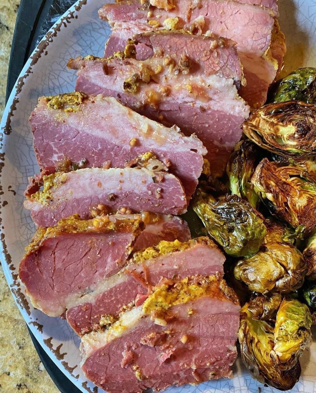 Corned beef slices next to cooked brussel sprouts