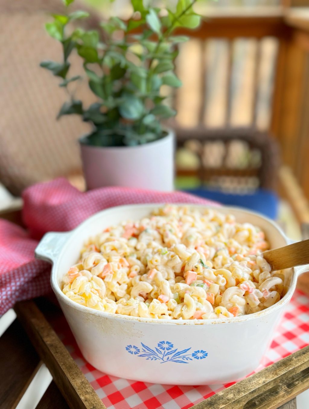 A close up of the completed macaroni salad with a wooden serving spoon