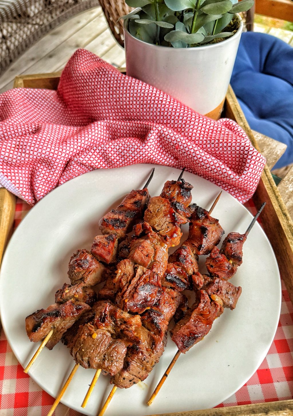 Beef skewers on a plate on a checker patterned tray