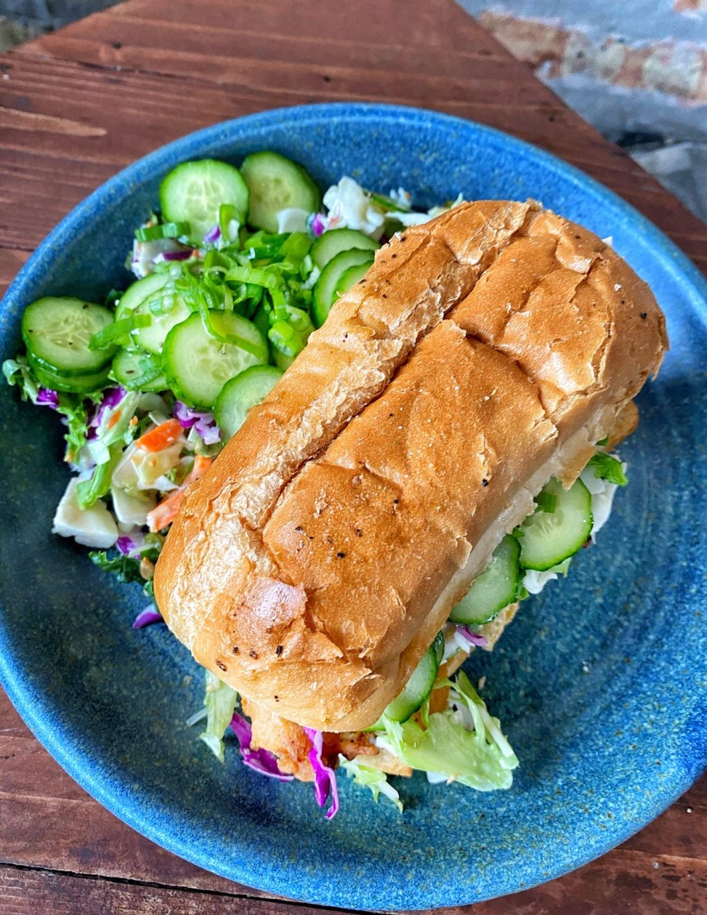 The finished Chicken Tender Sub on a blue plate with a side salad seen from above
