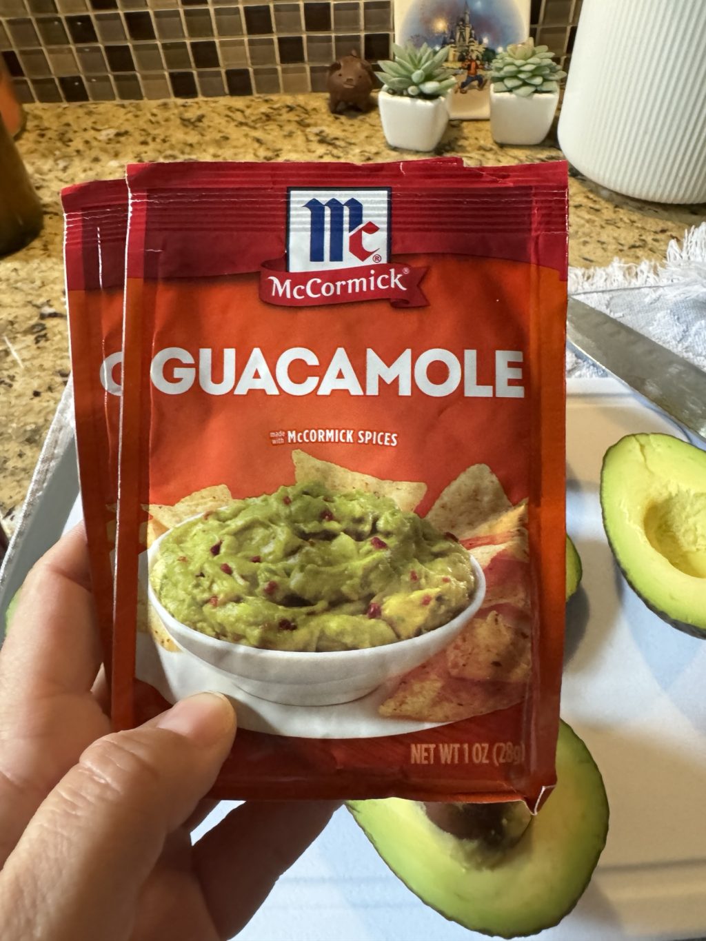 Two packets of McCormick Guacamole spices being held by me